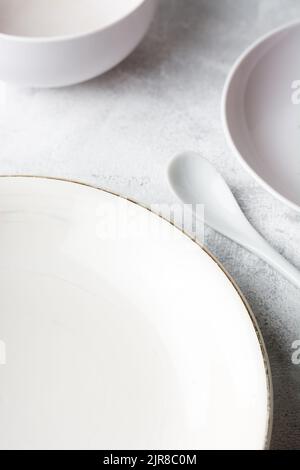 empty white plates with cup and spoon on a white textured table top, white color tone food photography background, soft-focus with copy space Stock Photo