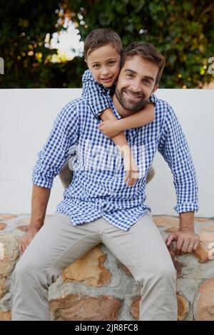 Weve got on matching outfits. Cropped portrait of a handsome young man and his son sitting outside. Stock Photo