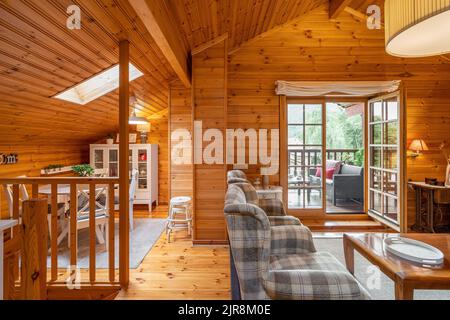 Beautiful interior of a living room with view of terrace and dining area in a wooden house Stock Photo