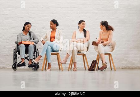 Inclusive group of women sharing idea and goals, planning and talking, sitting together at work. Diverse creative team chatting, brainstorming Stock Photo