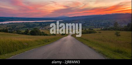Road running through mountain landscape during spectacular sunset Stock Photo