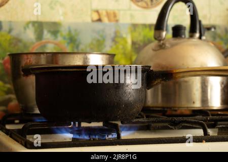 a dirty saucepan stands on a dirty gas stove in the kitchen at home, cooking soup on the stove, gas stove, kitchen Stock Photo