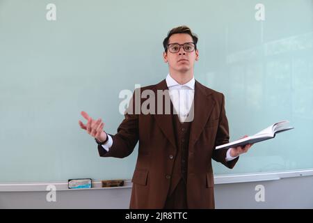 Blond Caucasian man in a suit and glasses giving a class and asking questions to his students. Teacher with questions about his class. Teacher in a classroom giving classes. High quality photo Stock Photo