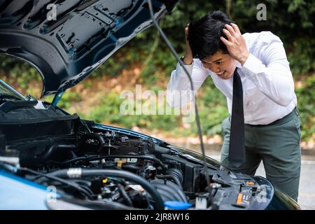 Asian businessman car broken breakdown, young stressed man having trouble car failure problem looking in frustration at failed engine in the morning, Stock Photo