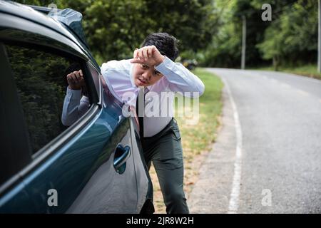 Asian businessman car broken has problems with car down during go to work in morning he pushing out of gas on road at countryside, business man have t Stock Photo