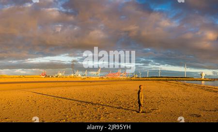 The setting sun over the Irish Sea creates a long shadow behind one of the Iron Men at Another Place on Crosby Beach.  This was captured as a multi im Stock Photo