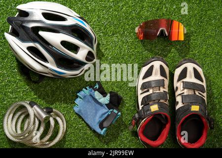 Flat lay composition with different cycling accessories on green grass background. Concept of sport lifestyle. Stock Photo