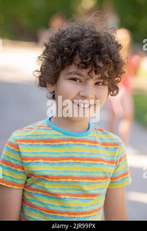 Friendly smiling boy with dark curly hair Stock Photo
