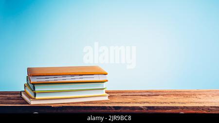 A stack of books and notebooks on desk or shelf. Education, studying and back to school concept Stock Photo