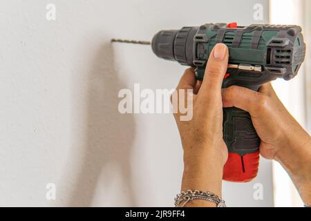 unrecognizable person using a drill to make a hole in his house. Stock Photo