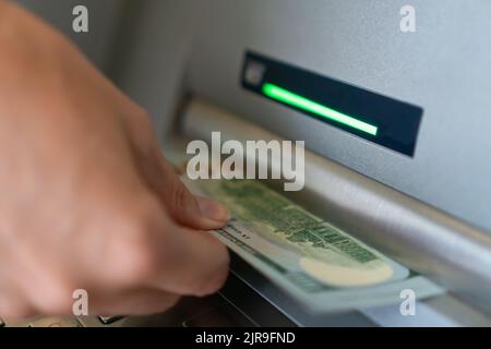 Close-up of a woman's hand withdrawing money from an ATM. Selective focus Stock Photo