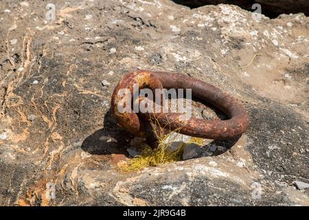 Old weathered rusty ring for tying boats closeup on pier Stock Photo