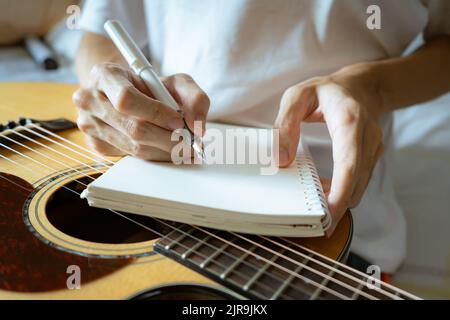 Musician using pen and notebook to write a song Stock Photo