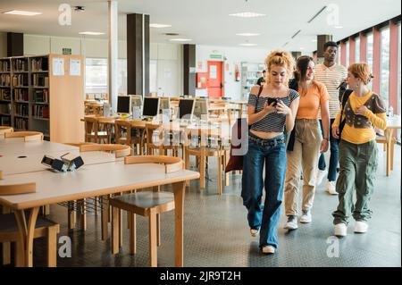 Diverse students leaving library together Stock Photo