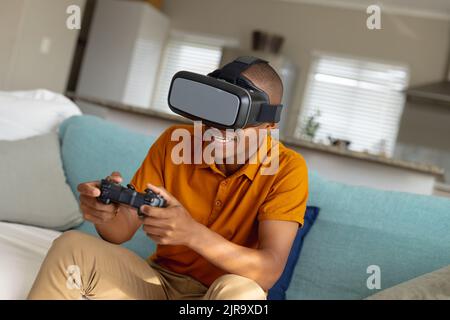 African american male teenager playing video games and using vr headset Stock Photo