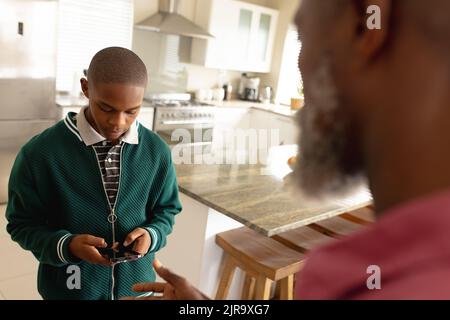 African american male teenager with his father using smartphone Stock Photo