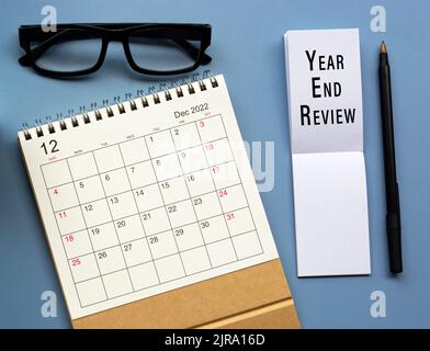 December 2022 desk calendar with Year End Review text written on notepad. Stock Photo