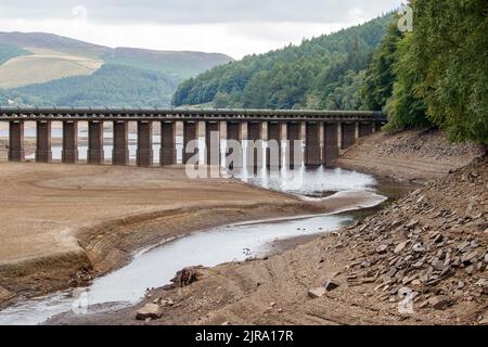 The water level is reduced to a small stream at the Upper end of the Ladybower reservoir near the visitor centre. The Ladybower reservoir during the dry and drought weather in the summer of 2022. Ladybower Reservoir is a large Y-shaped, artificial reservoir, the lowest of three in the Upper Derwent Valley in Derbyshire, England. Stock Photo