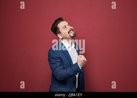 Portrait of playful bearded businessman having fun and looking up. Men wearing official style suit. Indoor studio shot Stock Photo