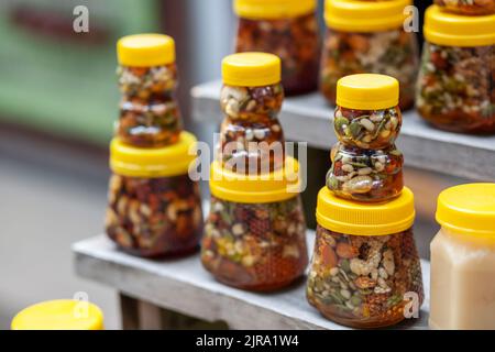 There are many jars of organic, natural honey on the counter for sale. Different honey, different colors in plastic cans are ready for sale at the hon Stock Photo
