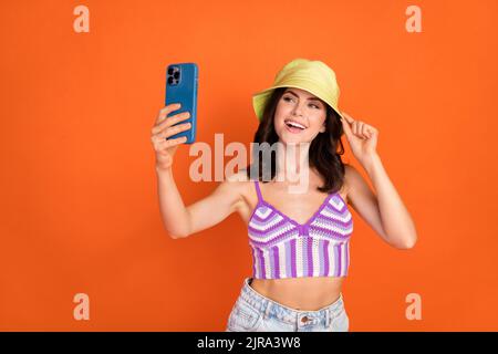 Photo of brunette impressed lady do selfie wear hat top isolated on orange color background Stock Photo