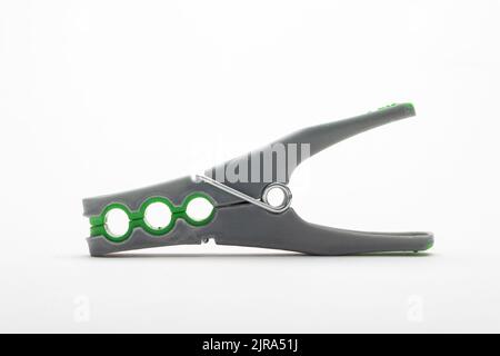 Grey plastic clothespin with green grip, isolated on white background Stock Photo