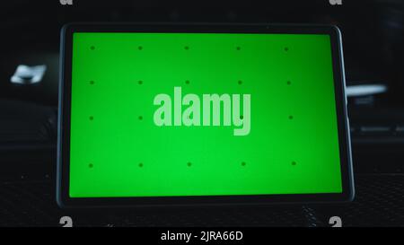 Modern gadget digital tablet computer with green screen chromakey on the hood of a black car during diagnostics in a car service Stock Photo