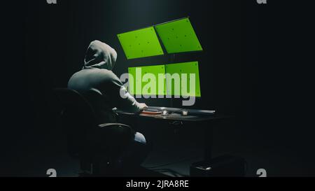 Concept shot of anonymous man in hoodie writing code to hack database while sitting at desk with computer monitors, with green screens chromakey in dim room of hacker base Stock Photo