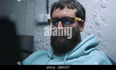 Web developer in glasses working in a laptop using software while sitting in a shelter during the bombing and during the war Stock Photo