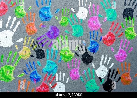 Colored hand palms on a gray wall. Children's handprints background. Charity, joy, party, holiday concept. High quality photo Stock Photo