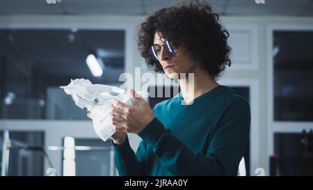 Man in casual clothes with curly hair examining plastic statuette from 3D printer while working in workshop of modern design studio Stock Photo