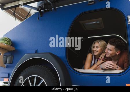 Happy young couple lying together in a van, enjoying vacation time together. Stock Photo