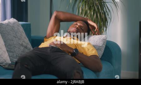 African American man in casual clothes lying on couch and sleeping in daytime at home Stock Photo