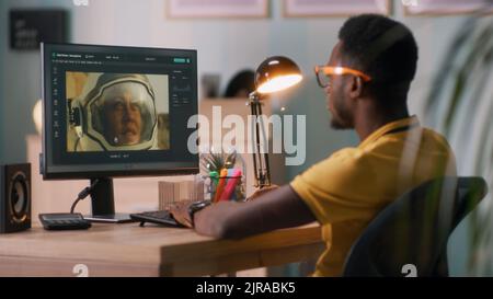Black man using software on modern computer to edit photo in editing application of cosmonaut space man while working remotely from home Stock Photo