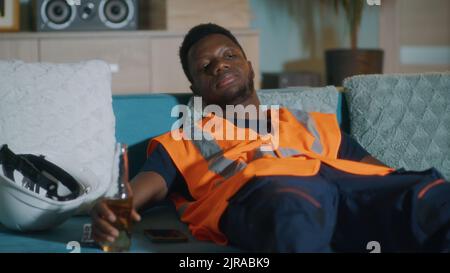 https://l450v.alamy.com/450v/2jrabk9/exhausted-african-american-male-in-orange-vest-changing-channels-on-tv-while-resting-on-couch-after-work-2jrabk9.jpg