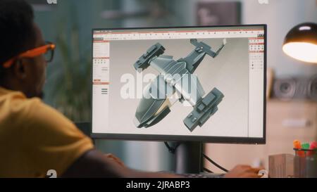 Black man using computer and creating 3D model of futuristic aircraft for videogame or movie while working from home Stock Photo