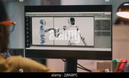 African American male creating 3D model of robot and rendering video for movie or computer game on computer while working from home Stock Photo