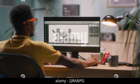 African American man creating 3D model and video for videogame on computer while sitting at table in light workplace at home Stock Photo