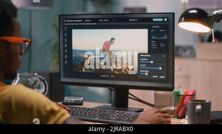 Black man adding 3D graphic into video with chromakey background while sitting at table and working in home office Stock Photo