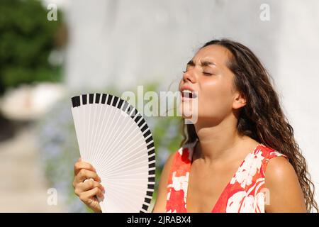 Woman suffering heat stroke in a town street on summer Stock Photo