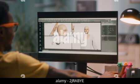 Black guy creating 3D model of bald human for movie or video game on computer during work in home office Stock Photo