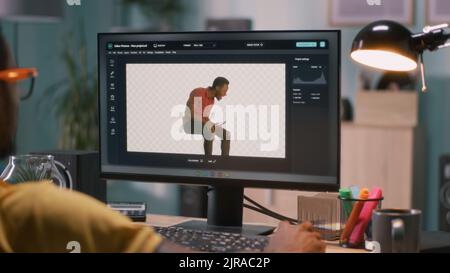 Black man adding 3D graphic into video with chromakey background while sitting at table and working in home office Stock Photo
