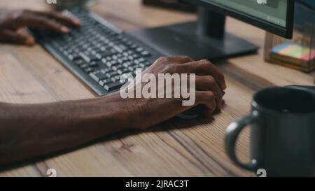 Unrecognizable African American man using computer keyboard and mouse while working on remote project Stock Photo
