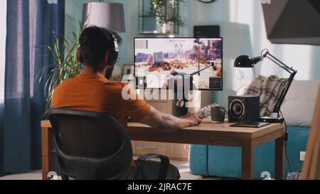 Bearded man controlling tank while playing videogame on modern computer in weekend at home Stock Photo
