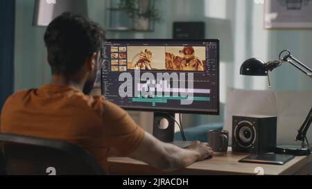 Back view of male content creator using computer to edit cosmonaut video during remote work from home Stock Photo