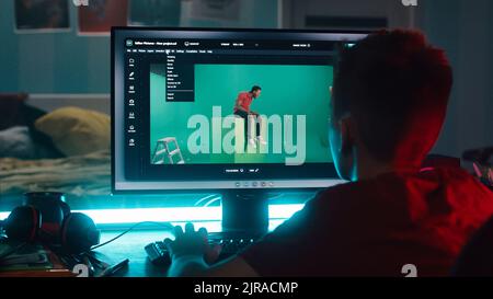 Unrecognizable teenager removing chromakey on photo and loading 3D background while learning to use editing software on computer at night at home Stock Photo