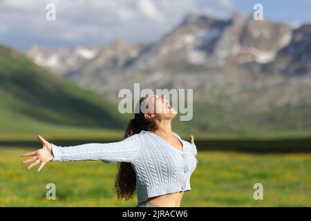 Excited casual woman screaming and outstretching arms in the mountain Stock Photo