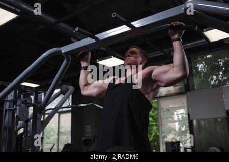 Strong muscular man doing pull ups at the gym Stock Photo
