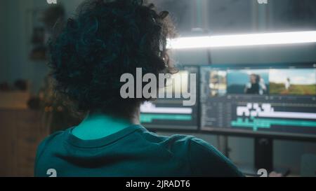 Guy in wireless headphones editing footage on computer while working on remote creative project in evening Stock Photo