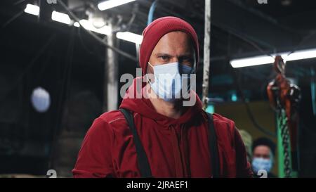 Adult man in medical mask looking at camera while working on fishing ship during pandemic Stock Photo